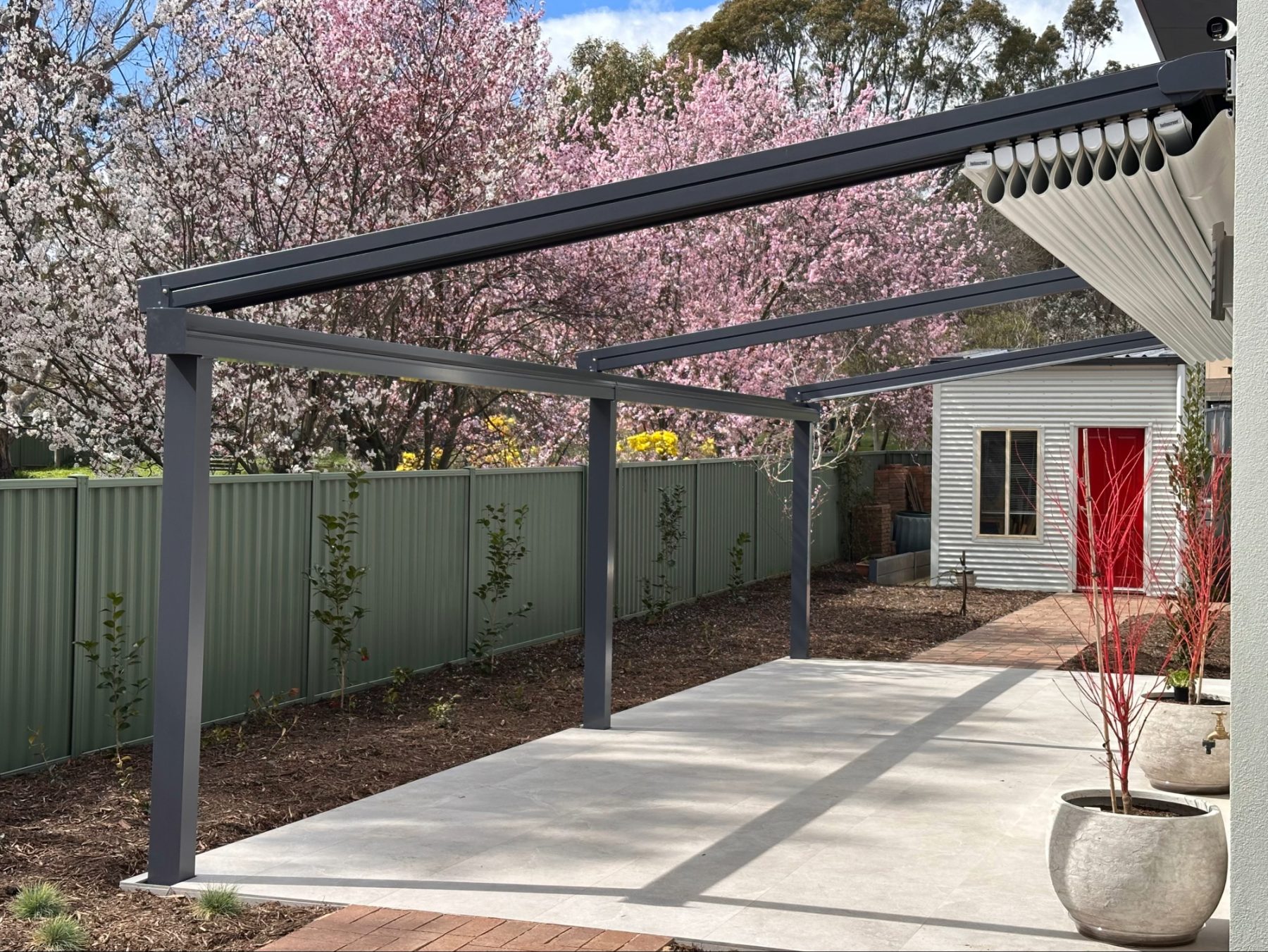 Helioscreen All Seasons retractable awning in open position — twin-field configuration installed on a residential pergola in Watson ACT, showing the cassette housing and guide arms